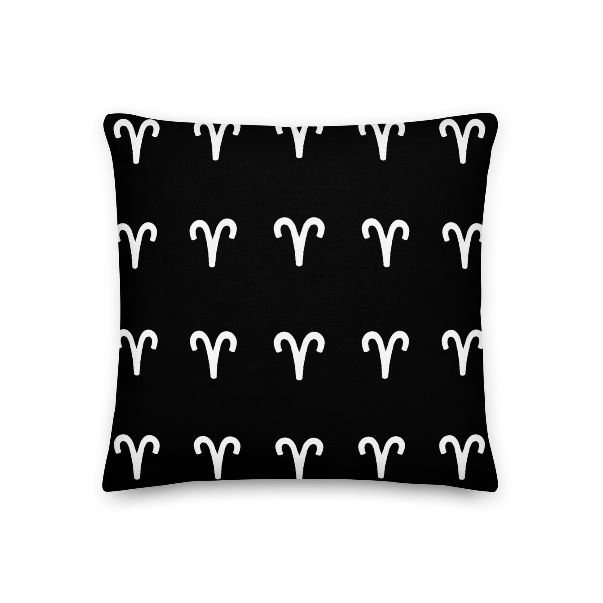 A luxury black pillow with a geometric pattern of white aries symbols, placed on a fluffy white surface.