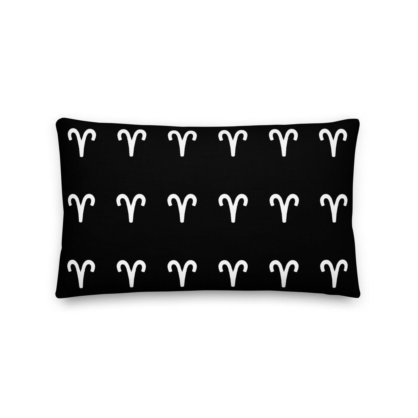 A luxury black pillow with a geometric pattern of white aries symbols, placed on a fluffy white surface.