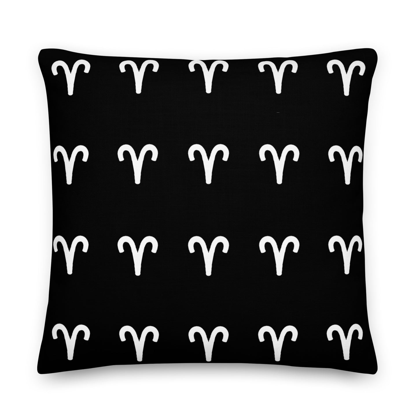 A luxury black pillow with a geometric pattern of white aries symbols, placed on a fluffy white surface.