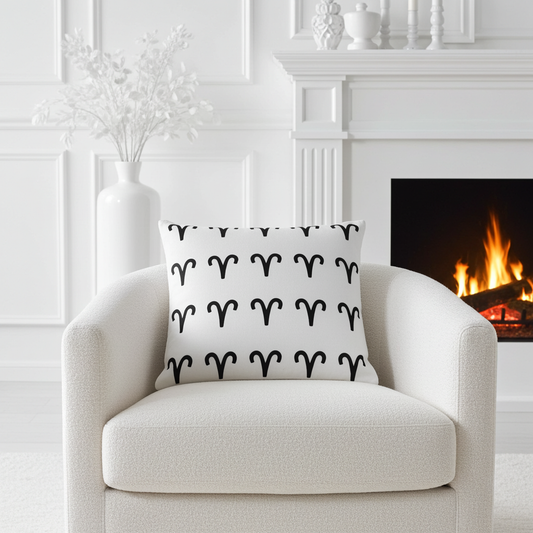 White armchair with a decorative pillow featuring black Aries patterns, placed in a room with a fireplace.