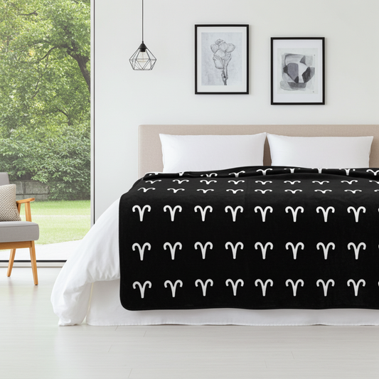 Bed with black blanket featuring white Aries patterns in a modern bedroom.