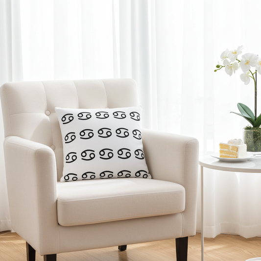 White armchair with a decorative pillow featuring black Gemini patterns in a bright room.