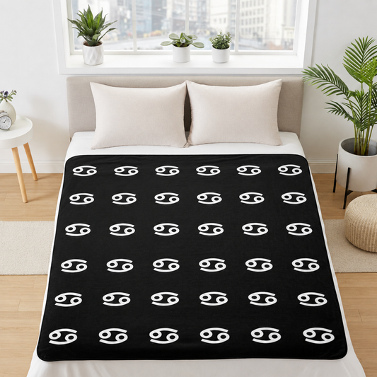 Black blanket with white cancerian symbol pattern on a bed in a bright room.
