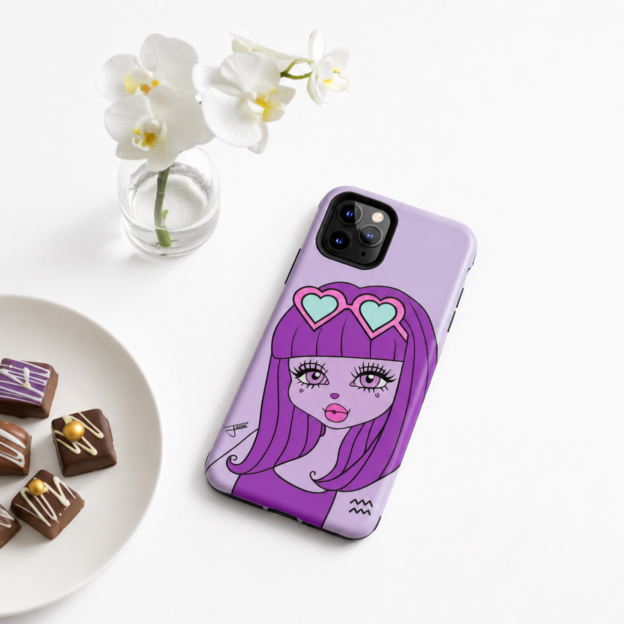 Phone case with an Aquarius character, placed on a white surface with flowers and pastries.