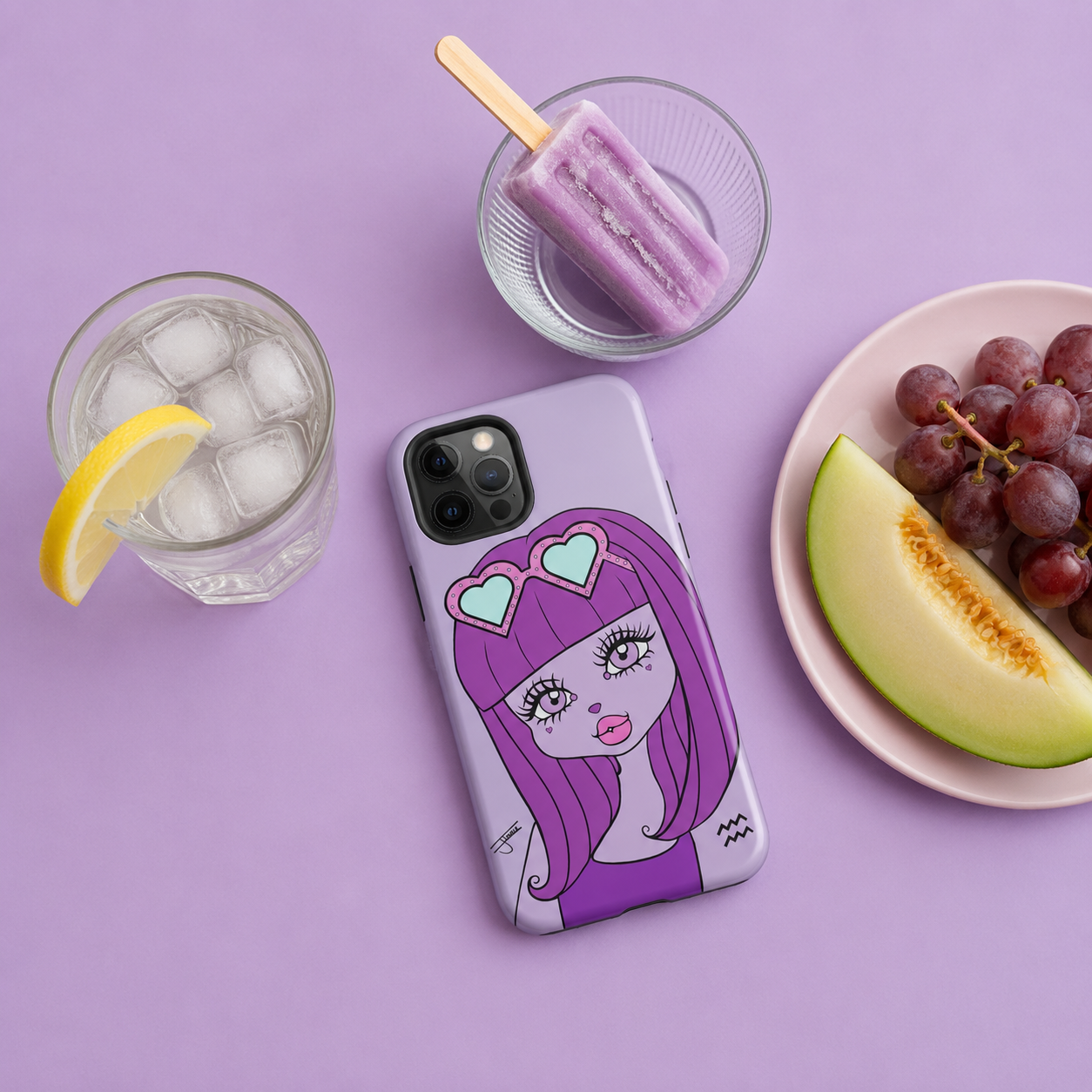iPhone case with an Aquarius character design on a purple table next to a plate of summer fruits, a glass of ice water, and a frozen popsicle.