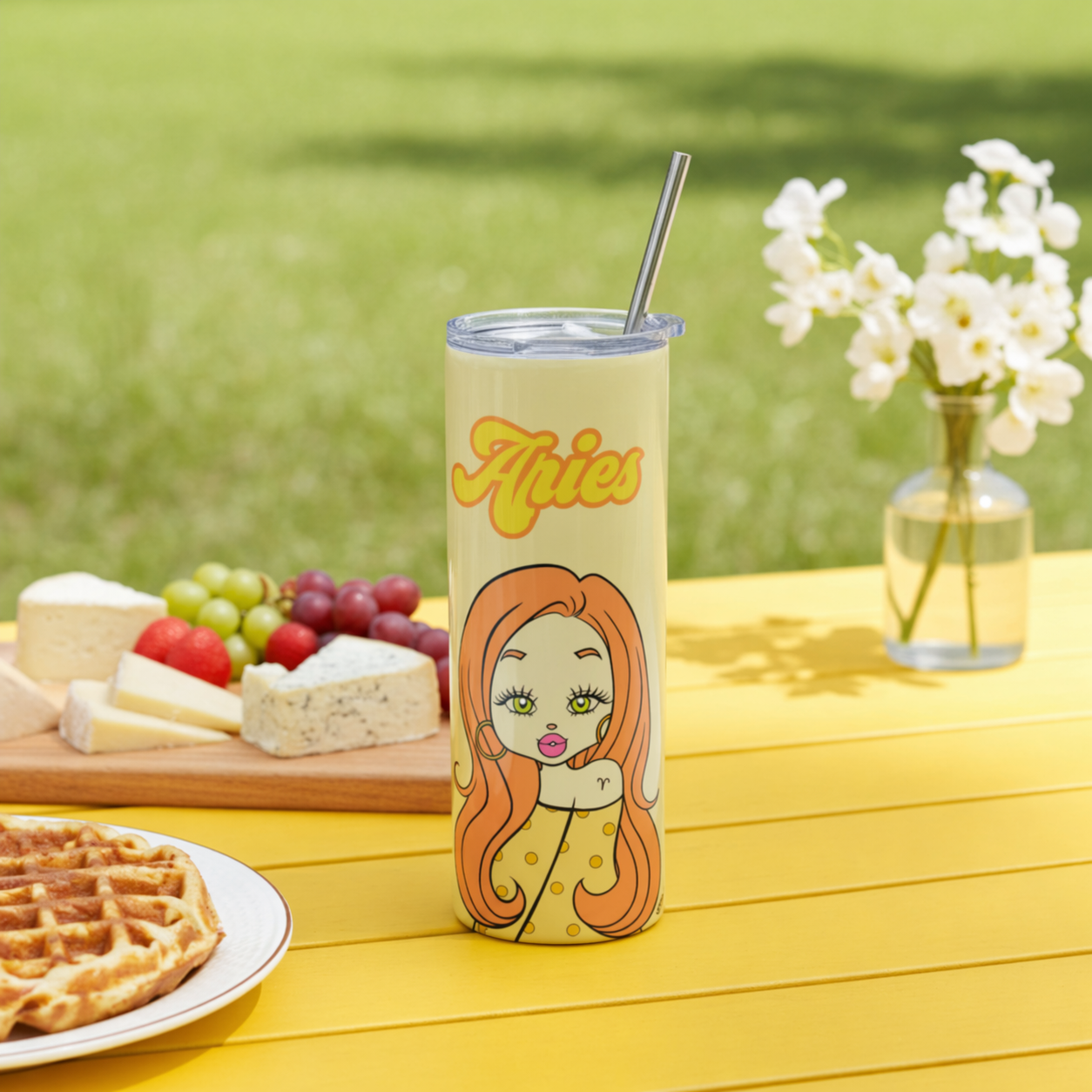 Tumbler with 'Aries' design on a picnic table with food and flowers