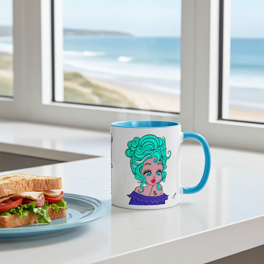 A white ceramic coffee mug with a capricorn character design, sitting on a white kitchen counter next to a sandwich on a plate. A window in the background shows a beach scene.