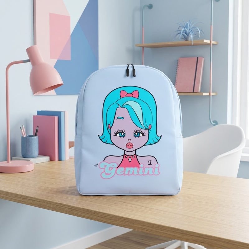 A light blue backpack with a cartoon Gemini girl graphic and the word 'Gemini' printed on the front, sitting on a wooden desk in a styled room with a pink lamp, books, and shelves.