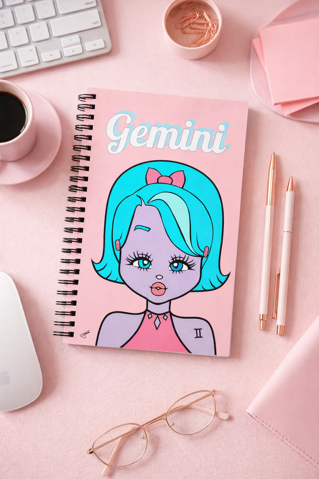 Notebook with a Gemini illustration on a pink desk with office supplies