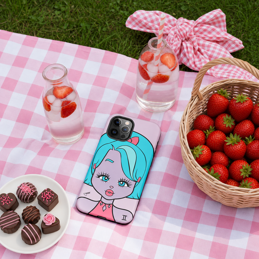 Picnic setup with a Gemini iphone case, strawberries, and chocolates on a pink checkered blanket.