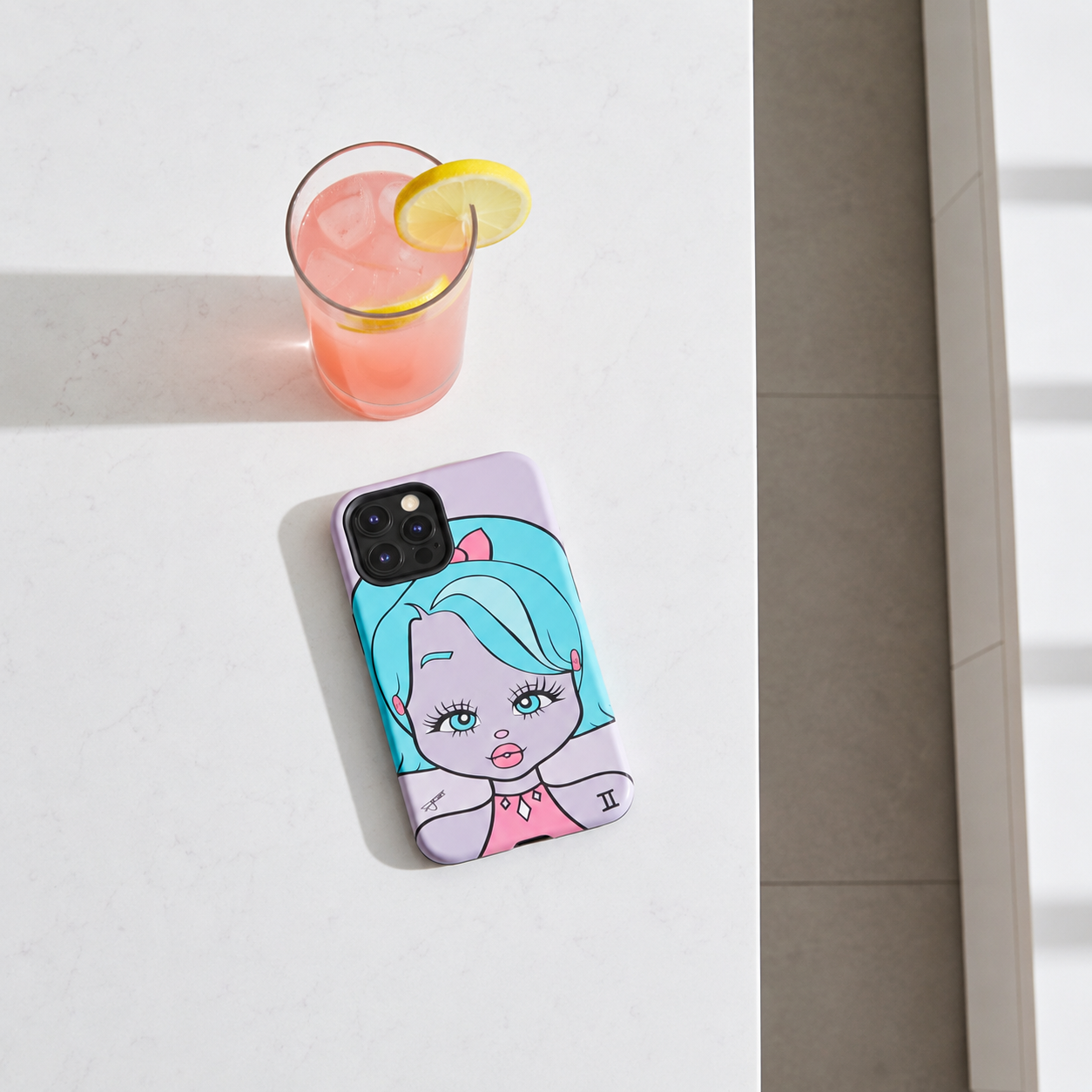 A phone case featuring a cartoon illustration of a girl with turquoise hair and a pink bow, shown on a light gray marble tabletop next to a glass of pink drink with a lemon slice.