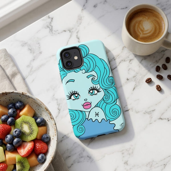 A light blue phone case featuring a stylized cartoon illustration of a woman with turquoise hair and a Pisces zodiac symbol, displayed on a white marble surface next to a cup of coffee, a bowl of fruit, and scattered coffee beans.