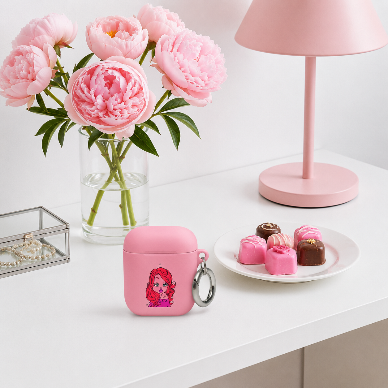 Airpod case with a Sagittarius character design on a dresser next to chocolates and a pink lamp.