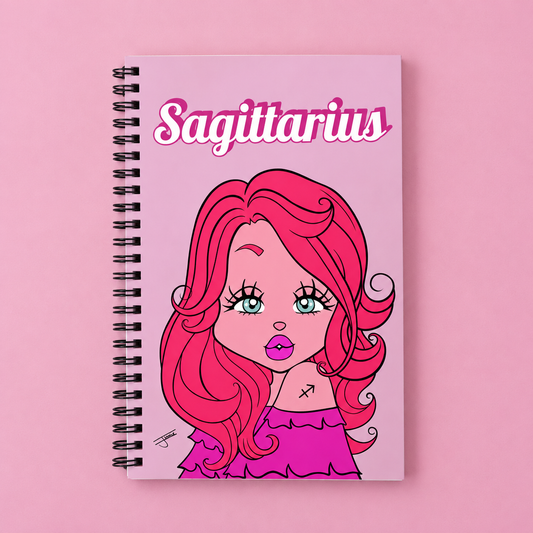 A spiral-bound notebook with a pink cover featuring a cartoon illustration of a woman with long pink hair and the word 'Sagittarius' in stylized pink lettering, set against a solid pink background.