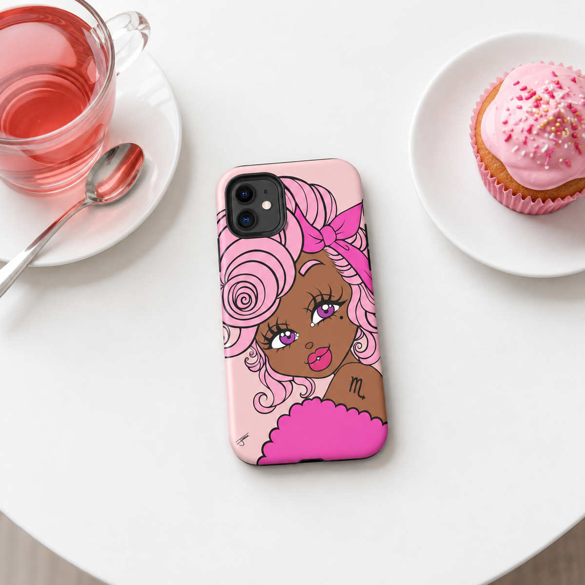 A pink phone case featuring a stylized cartoon illustration of a woman with pink hair and a pink bow, placed on a white table next to a pink drink and a pink frosted cupcake.