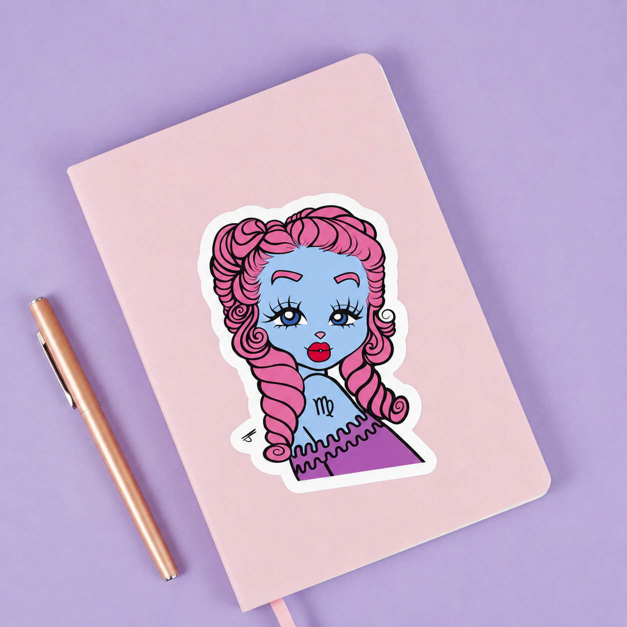 Sticker of a Virgo character on a pink notebook with a pen next to it.