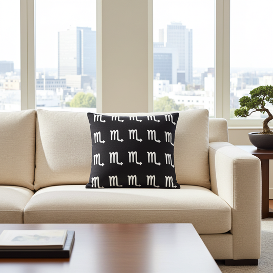 Beige sofa with a black pillow featuring Scorpio pattern, large windows with cityscape view.