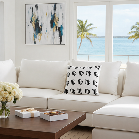 Modern living room with a white sofa, decorative virgo pillow, and a view of the ocean through large windows.